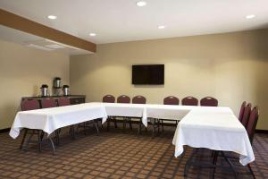 オデッサにあるMicrotel Inn & Suites by Wyndham Odessa TXの白いテーブルと椅子、テレビが備わる会議室