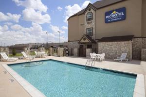 a swimming pool in front of a hotel at Microtel Inn & Suites by Wyndham Odessa TX in Odessa