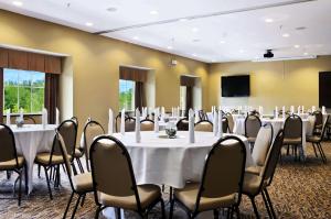 Microtel Inn & Suites by Wyndham Marietta في ماريتا: قاعة اجتماعات مع طاولات وكراسي وشاشة