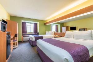 a hotel room with two beds and a flat screen tv at Microtel Inn & Suites by Wyndham Auburn in Auburn