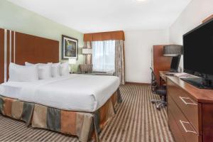 ein Hotelzimmer mit einem Bett, einem Schreibtisch und einem TV in der Unterkunft Ramada by Wyndham Carlyle in Carlyle