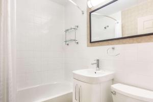 Howard Johnson Inn by Wyndham Kingston في كينغستون: حمام أبيض مع حوض ومرآة