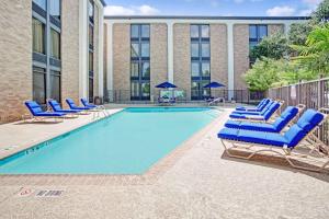 a swimming pool with blue lounge chairs and a building at Wingate by Wyndham Richardson in Richardson