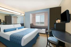 ein Hotelzimmer mit einem Bett, einem Schreibtisch und einem TV in der Unterkunft Microtel Inn & Suites by Wyndham Stanley in Stanley