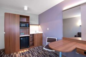 Microtel Inn & Suites by Wyndham Philadelphia Airport Ridley Park في Ridley Park: غرفة صغيرة مع طاولة ومطبخ