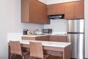 a kitchen with wooden cabinets and a stainless steel refrigerator at Microtel Inn & Suites by Wyndham Kirkland Lake in Kirkland Lake