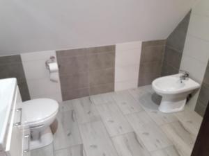 a bathroom with a white toilet and a sink at Topolowa in Zgierz