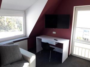 Zimmer mit einem Schreibtisch, einem TV und einem Sofa in der Unterkunft Topolowa in Zgierz