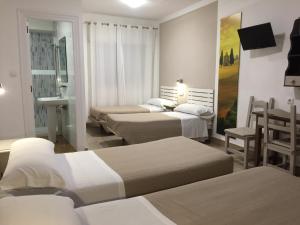 um quarto de hotel com quatro camas e uma mesa e cadeiras em Hostal Puerto Beach em Motril