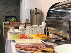 a buffet with meats and vegetables on a table at Bapsha Guesthouse in Mestia