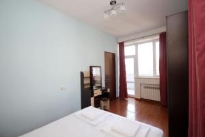 a white bedroom with a bed and a window at Apartments Emili in Yerevan