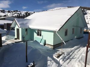 a house with snow on the ground in front at Alakol-Jyrgalan Guest House in Dzhergalan