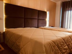 um quarto com uma cama grande e uma grande cabeceira. em Hotel Europa em Vila Pouca de Aguiar