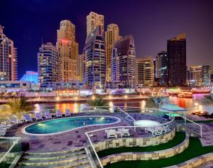 a city skyline at night with a swimming pool at Pearl Marina Hotel Apartments in Dubai