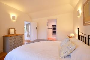 a bedroom with a white bed and a dresser at Cobblestone Cottage in Penzance