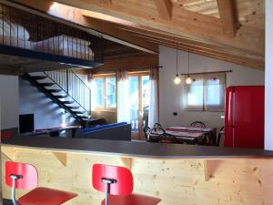Habitación con encimera con sillas rojas y nevera roja. en Pista Stelvio Loft Lumière, en Bormio
