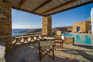 un patio con mesa y sillas junto a una piscina en Luxury Cycladic Villa-Enjoy Infinity Pool Sunsets, en Koundouros
