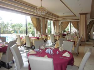 a restaurant with tables and chairs and a chandelier at Atlantic Palace Hotel in Pointe-Noire