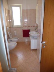 een badkamer met 2 toiletten, een wastafel en een raam bij Appartamento Iolanda in Tortoreto Lido
