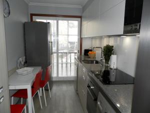 uma cozinha com um balcão e uma mesa com cadeiras vermelhas em Silgar I em Sanxenxo
