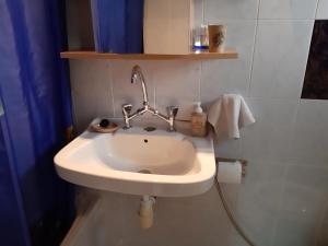 un lavandino bianco in un bagno con una tenda blu di Jenny's house,Agiou Ioannou 103 a Artemida Altre 15 foto