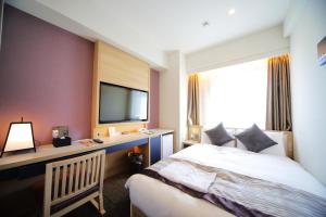 a hotel room with a bed and a television at Hotel Sunroute Asakusa in Tokyo