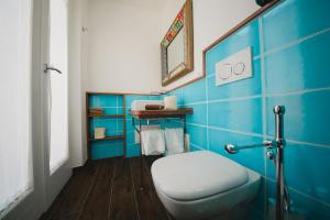 een blauw betegelde badkamer met een toilet en een spiegel bij S'Arena Dorada Deluxe Apartment in Alghero