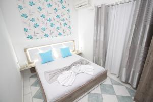 a white bedroom with a bed with blue pillows at Apartments Cota Guesthouse in Ulcinj
