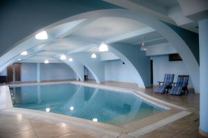 a swimming pool in a building with blue ceilings at Imperial Hotel IH in Elbasan