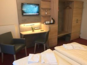 a room with two beds and a desk and a tv at Landhotel Stüer in Altenberge
