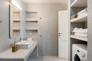 a bathroom with a sink and a washing machine at Xyla Beach Studios in Melissaki