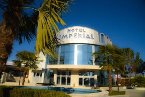 a hotel imperial with a palm tree in front of it at Imperial Hotel IH in Elbasan