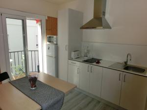 a kitchen with white cabinets and a table with a window at Rosesapparts Estudios & Parking in Roses