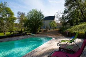 einen Pool mit zwei Stühlen und ein Haus in der Unterkunft Le Moulin de Bois Coûtant in Vivonne