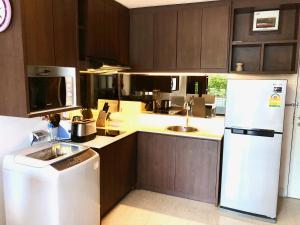 una cucina con mobili in legno e un frigorifero bianco di The Aristo by Holy Cow, 2-BR, 60 m2, pool view a Surin Beach
