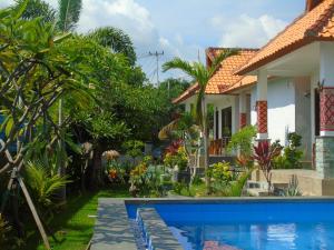 a villa with a swimming pool in front of a house at Kuri Garden Cottage in Nusa Penida
