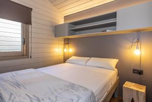 a bedroom with a white bed and a shelf at Bungalows Stel-Puigcerdà in Puigcerdà
