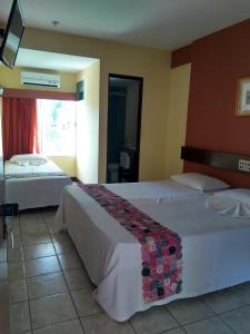 a hotel room with two beds and a window at Hotel Encosta da Serra CRATO CE in Crato