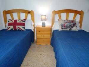 a bedroom with two beds with blue sheets and a night stand at BONAIRE - PRIMERA LÍNEA DE PLAYA in Playa de Gandia +60 photos