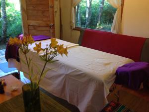 1 dormitorio con 1 cama con un jarrón con flores en Eco-Cabañas Quetroleufu, en Pucón