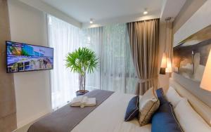 1 dormitorio con 1 cama, TV y ventana en Oceanstone by Holy Cow, 2-BR, 60 m2, tree view en Bang Tao Beach