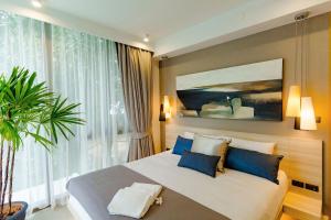 a bedroom with a large bed with blue pillows at Oceanstone by Holy Cow, 2-BR, 60 m2, tree view in Bang Tao Beach