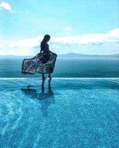 a woman sitting on the edge of a swimming pool at Petra Thea in Kalamata
