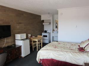 um quarto com uma cama e uma cozinha com uma mesa em Peace Villa Motel em Dawson Creek