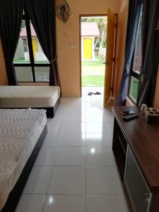 a bedroom with two beds and a desk and a door at Mutiara Chalet in Melaka