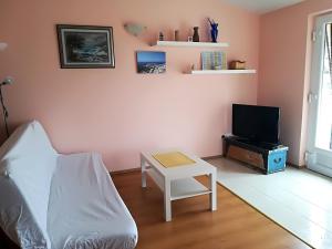 ein Wohnzimmer mit einem Sofa, einem TV und einem Tisch in der Unterkunft Apartman Rosanda in Premuda