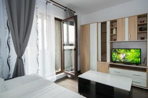 a bedroom with a bed and a tv and a window at Rezident militari in Chiajna