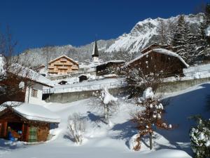 a snow covered building with a church with a snow covered mountain at Chalet Gerbera in Wengen