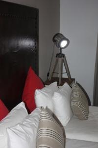 a bed with white pillows and a light on a tripod at Bush Pillow Guest House in Otjiwarongo