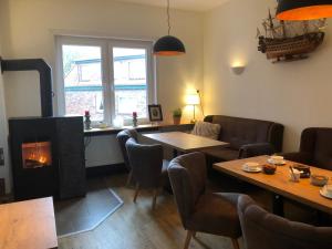 a living room with a fireplace and a table and chairs at Heeren's Hotel Garni in Bensersiel